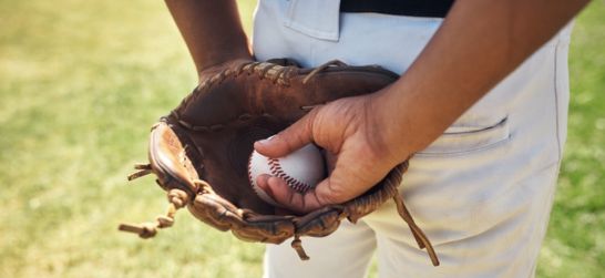 a professional baseball player holds a baseball in his glove behind his back