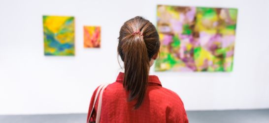 a girl stands in an art gallery admiring paintings